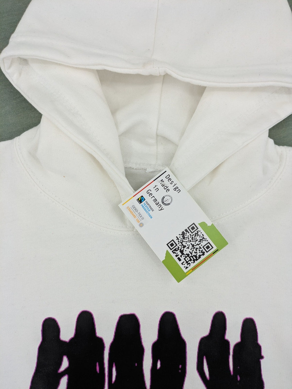 KATSEYE white zip-through hoodie with black silhouette graphic and logo, classic pullover style.