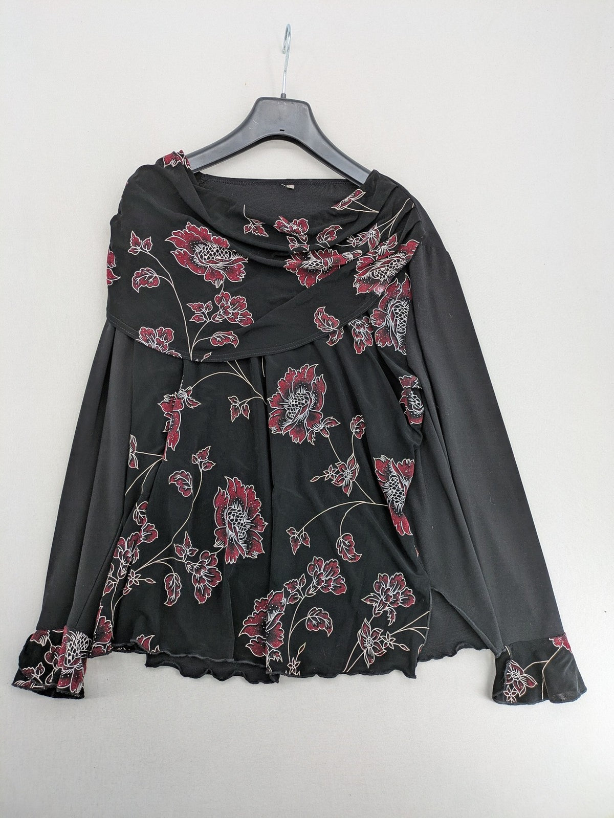 Damen black top with burgundy and white floral print, waterfall collar, and ruffled sleeves.