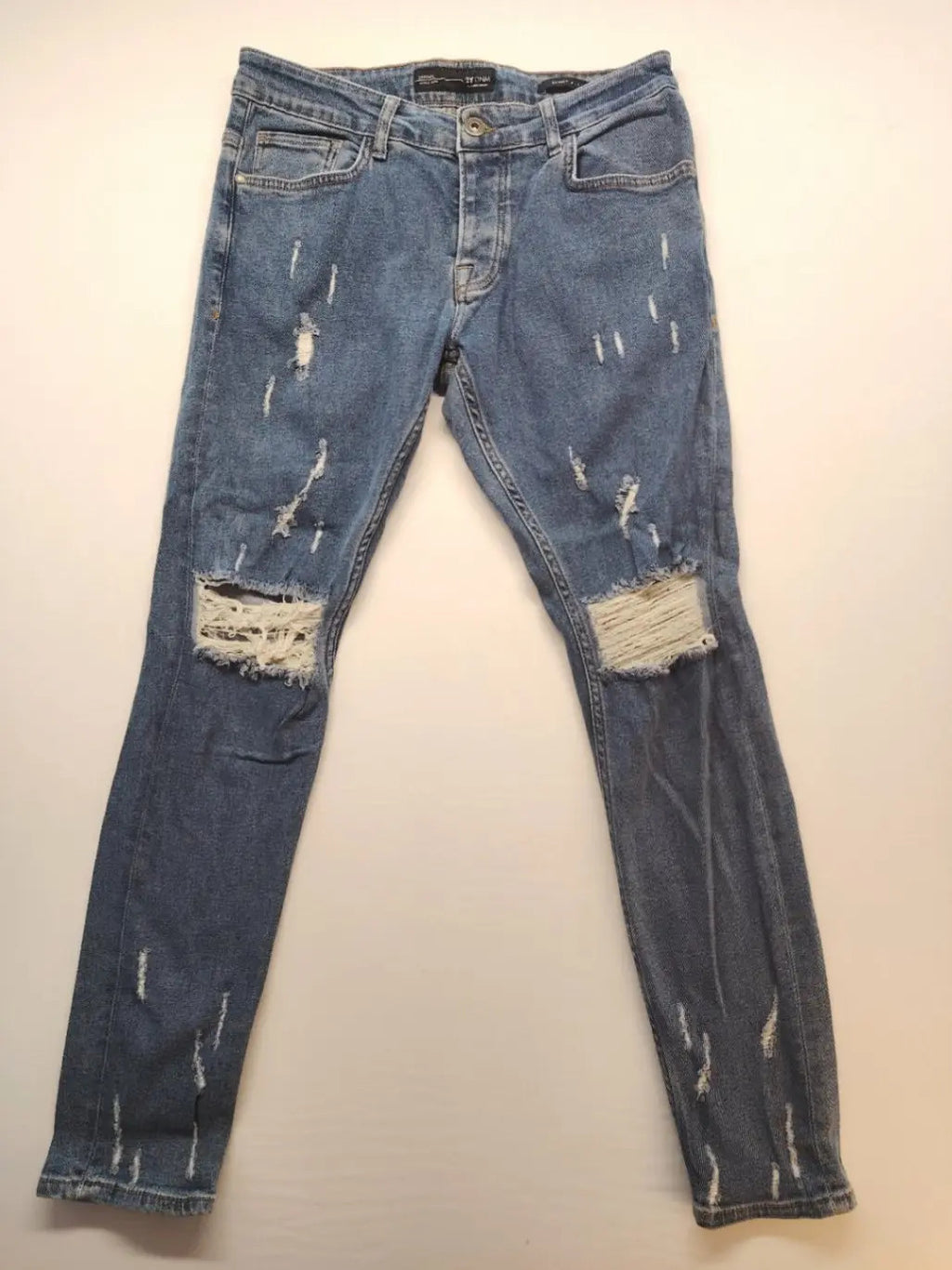 Damen blue skinny jeans with ripped details, five-pocket style, and classic button closure.