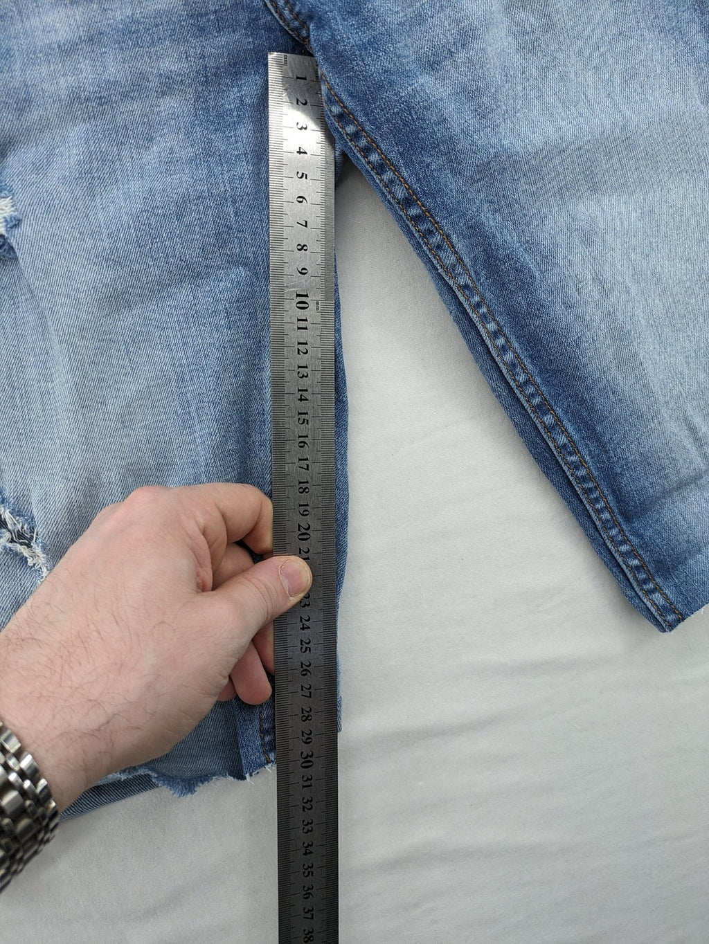 Denim blue distressed jeans shorts with frayed edges and a trendy used look.