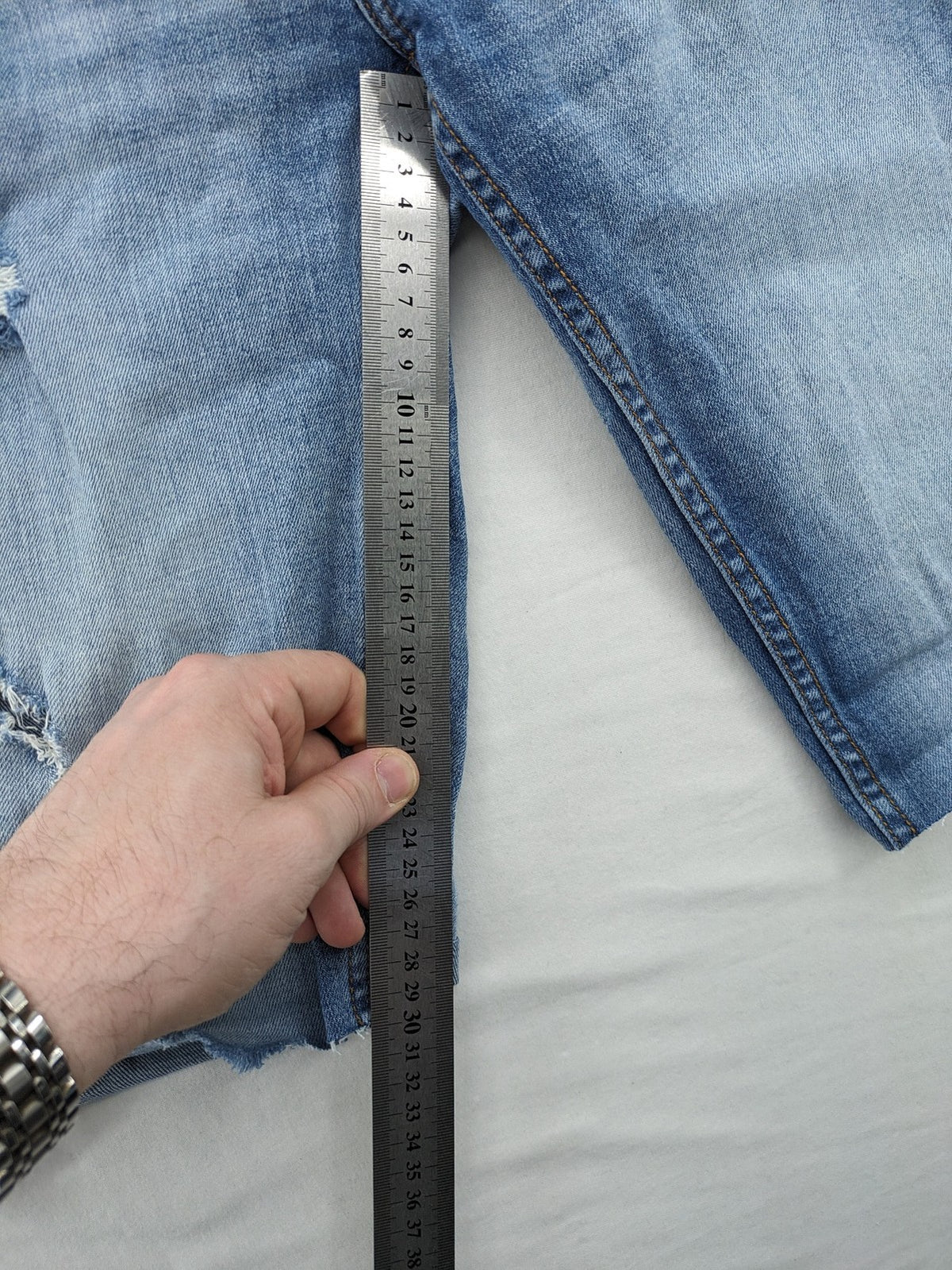 Denim blue distressed jeans shorts with frayed edges and a trendy used look.