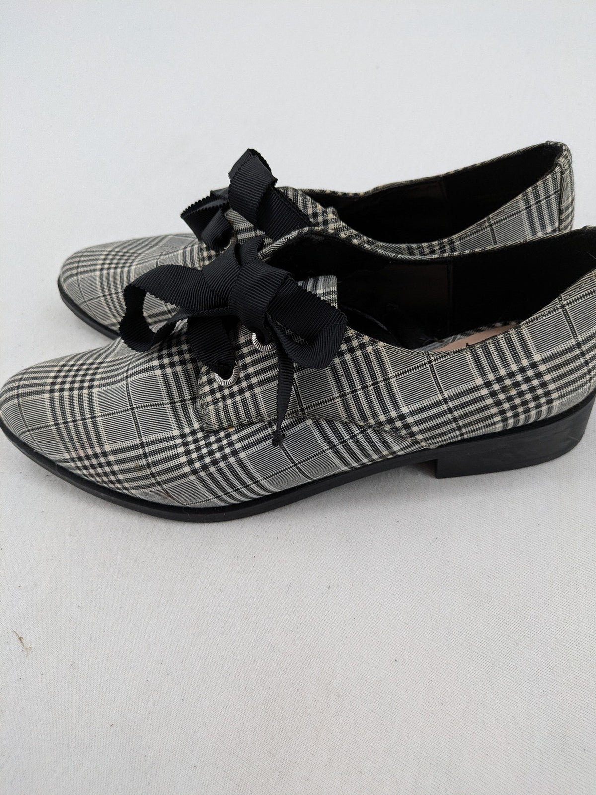 ALDO black and white checkered loafers with decorative bow detail and pointed toe.