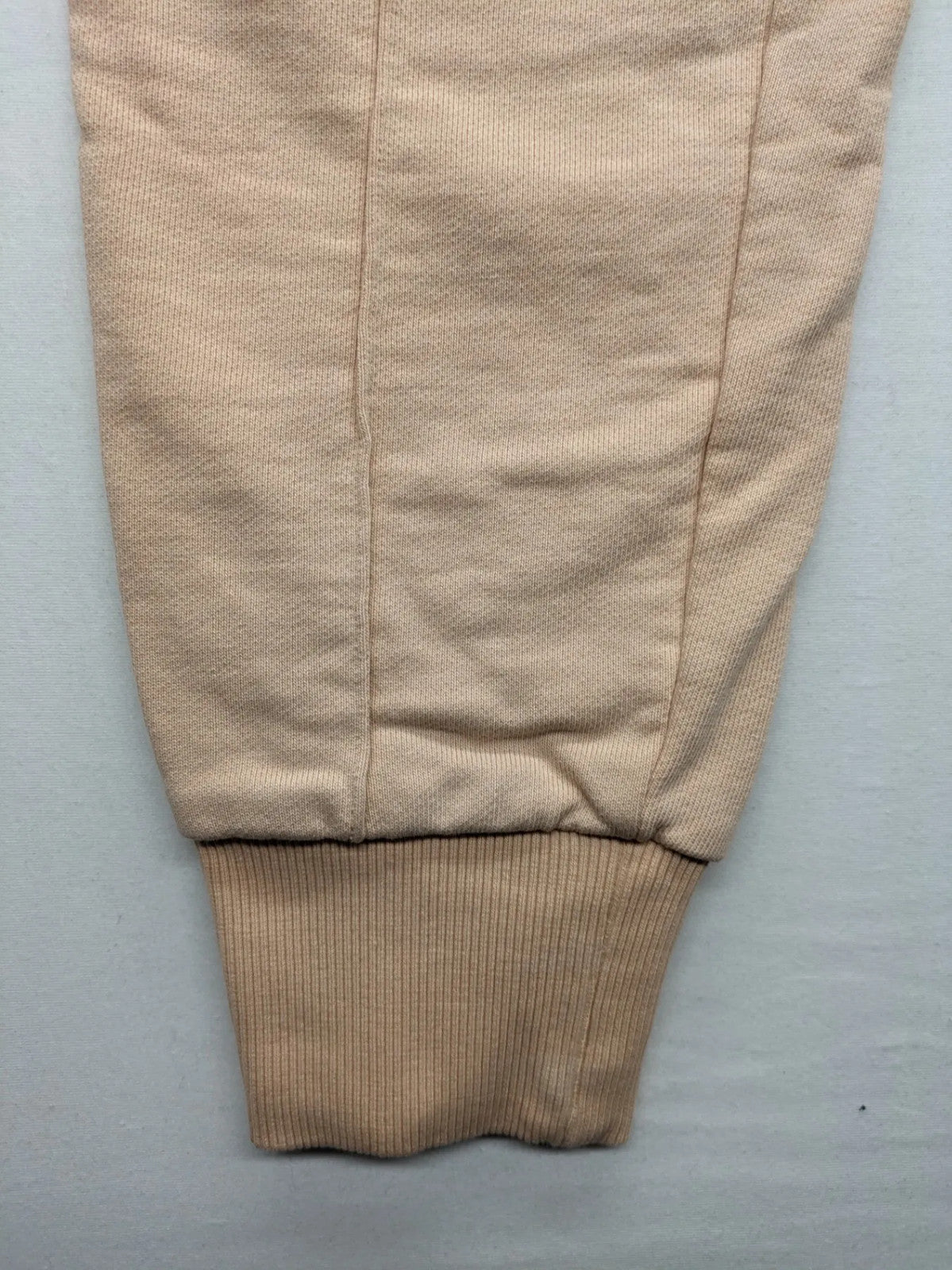 Hummel beige jogging pants with adjustable drawstring, embroidered logo, and ankle cuffs.