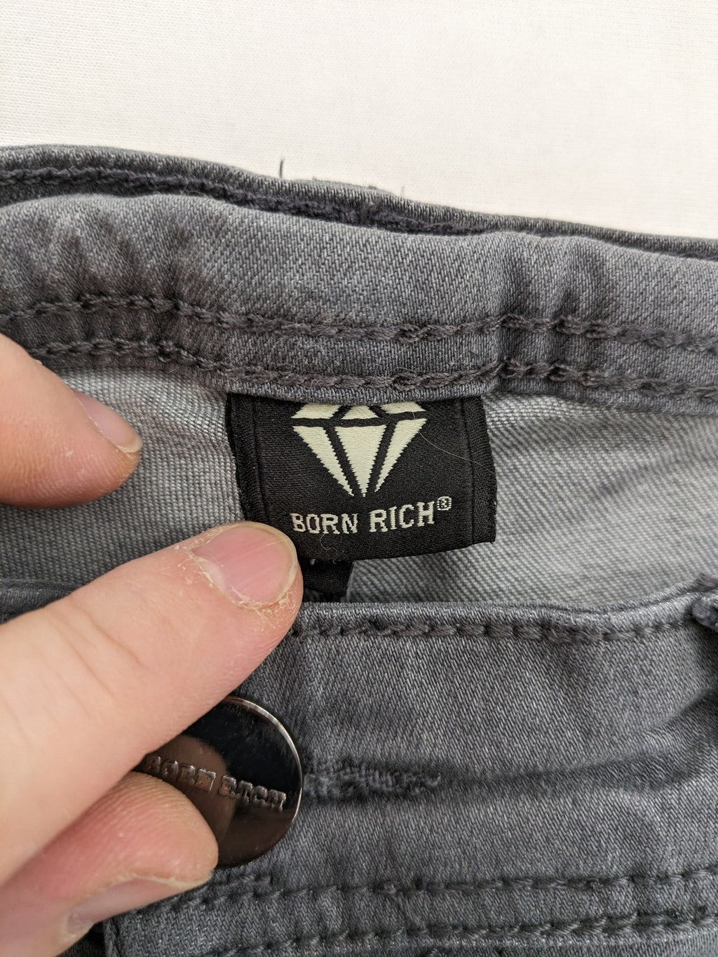 Born Rich grey slim fit jeans with button fly and washed denim texture.