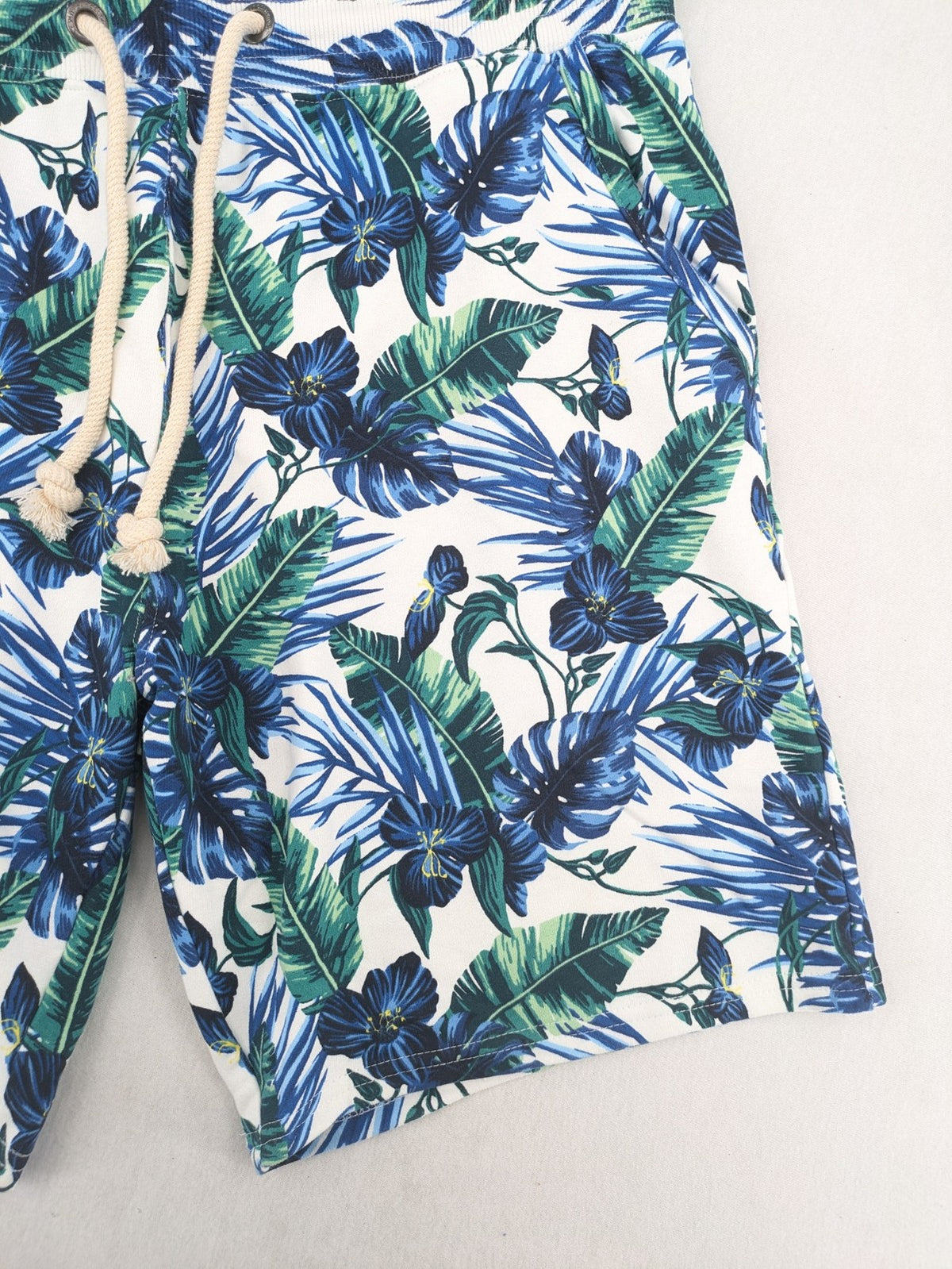 Nils Sundström blue and green tropical floral shorts with white background and elastic waistband.