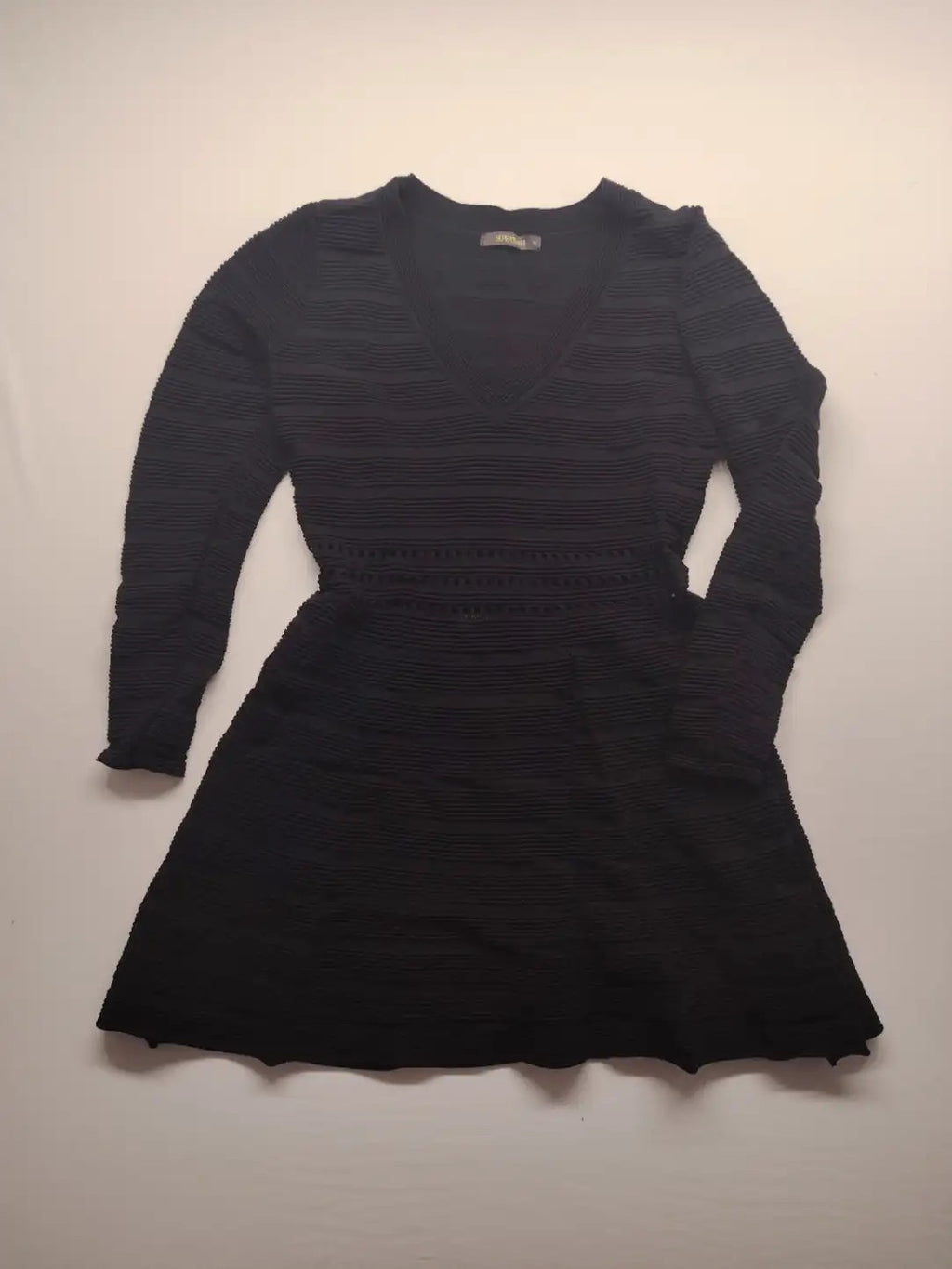 Supertuga black ribbed dress with V-neck, long sleeves, and pointelle detail at waist.