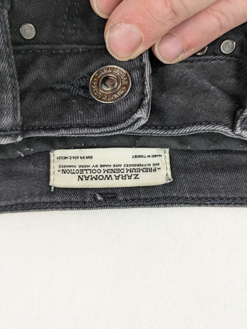 Zara Woman black skinny jeans with distressed details, silver studs, and frayed hem.
