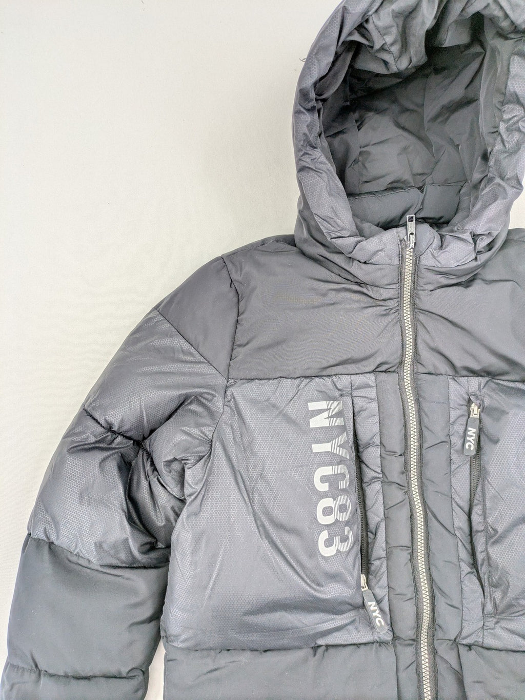 C&A black puffer jacket with NYC83 graphic, hood, and multiple pockets.