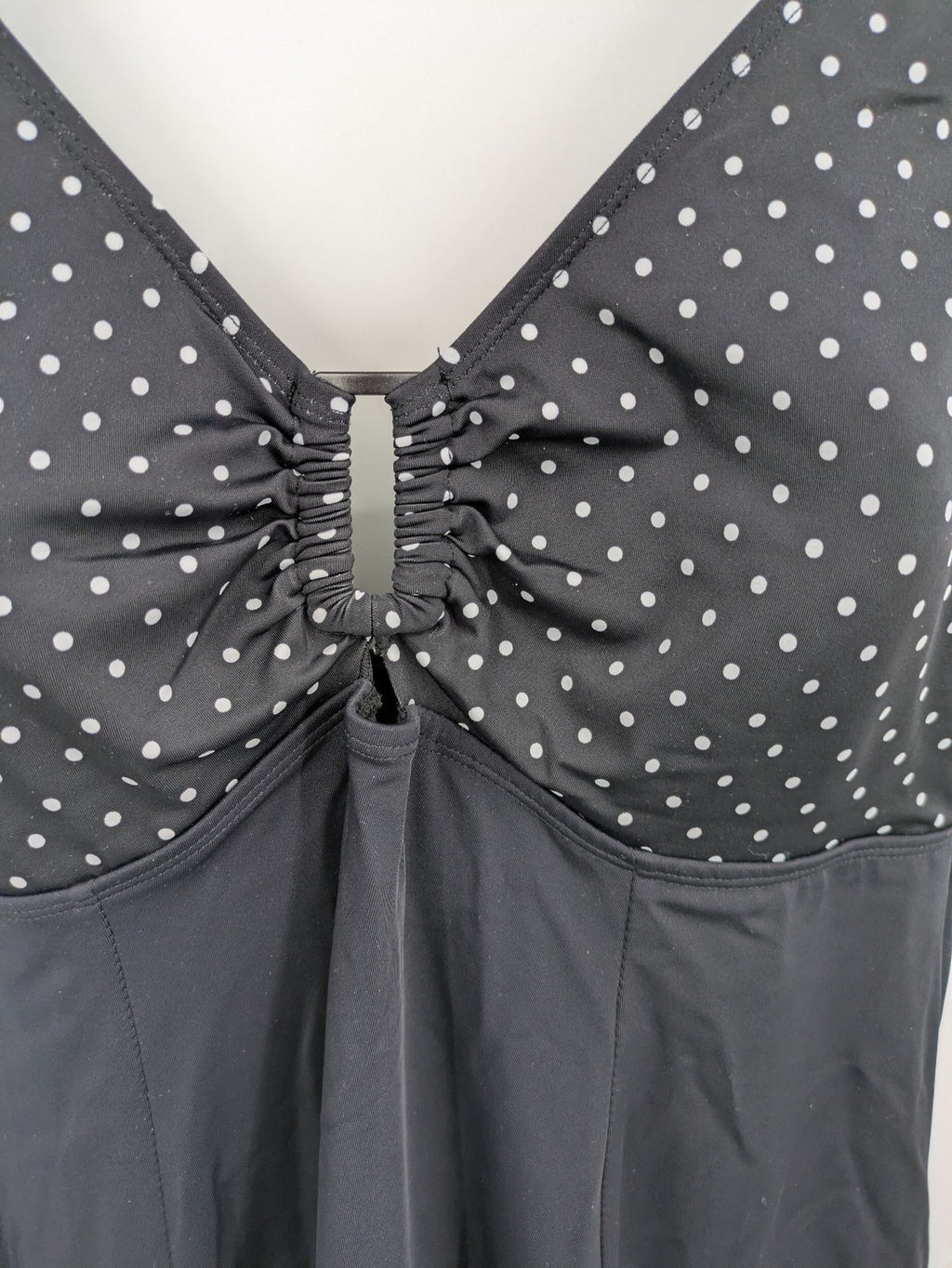 Elegante black swimsuit with white polka dots, V-neck, adjustable straps, and padded cups.