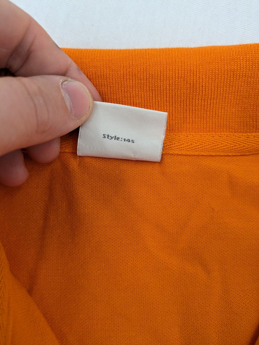 Teejays orange polo shirt with embroidered logo, classic collar, and button placket.