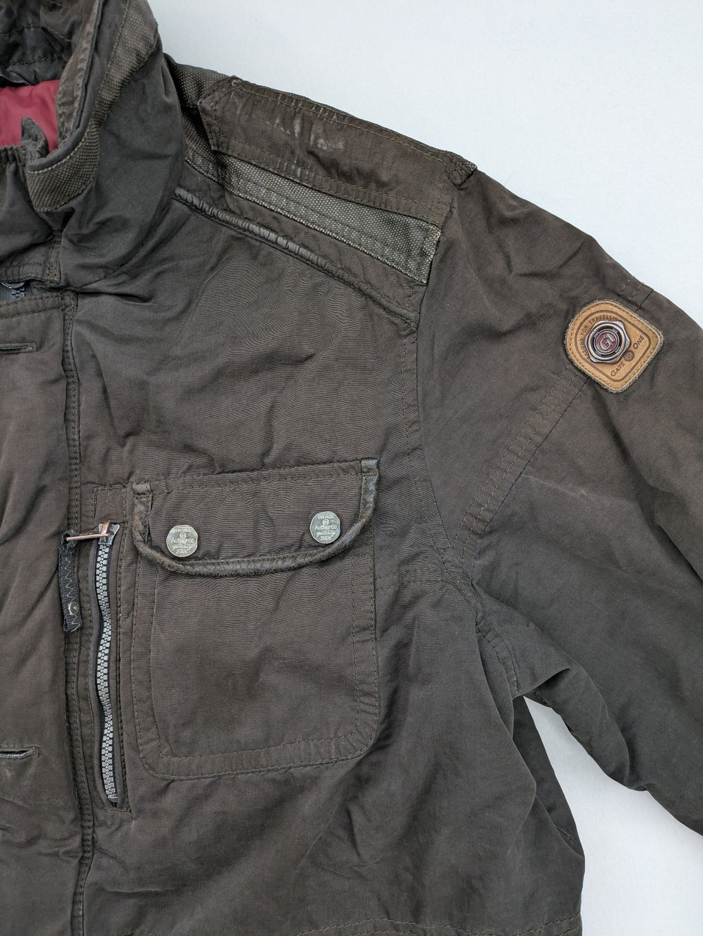 Gate One brown field jacket with plaid lining, multiple pockets, and zip-button closure.