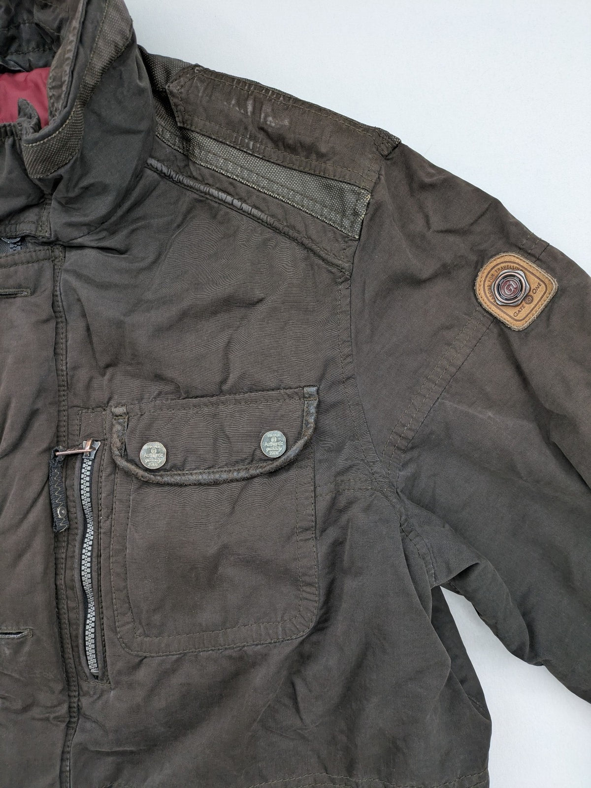 Gate One brown field jacket with plaid lining, multiple pockets, and zip-button closure.