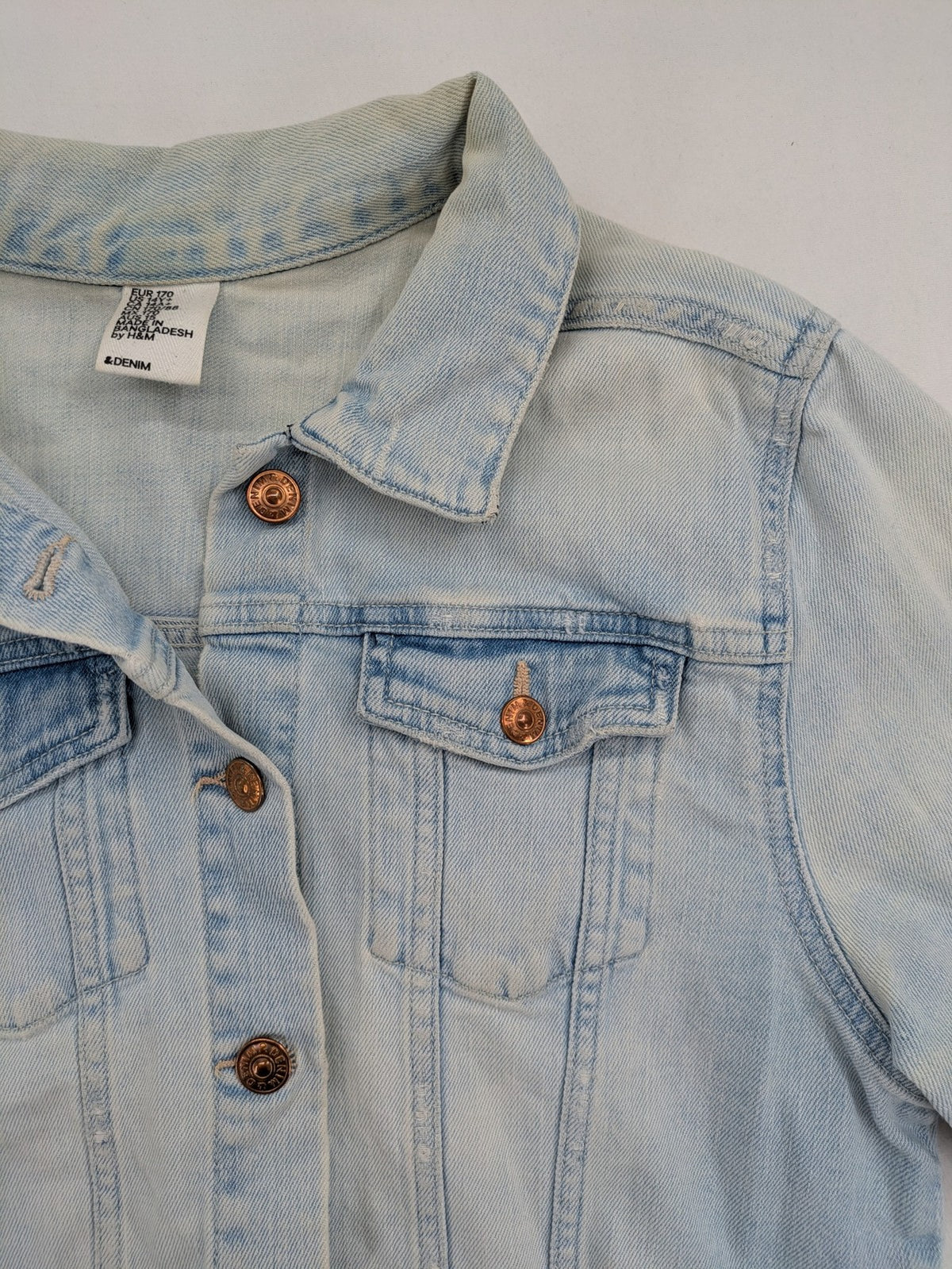 H&M denim jacket light blue classic trucker style with button placket and chest pockets.