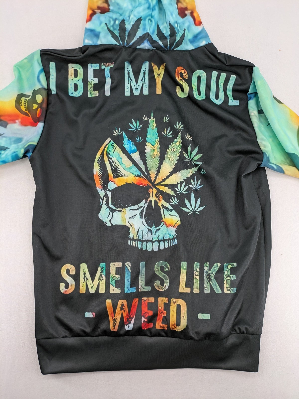 Skull tie-dye hoodie blue green with cannabis leaf graphic and bold text.