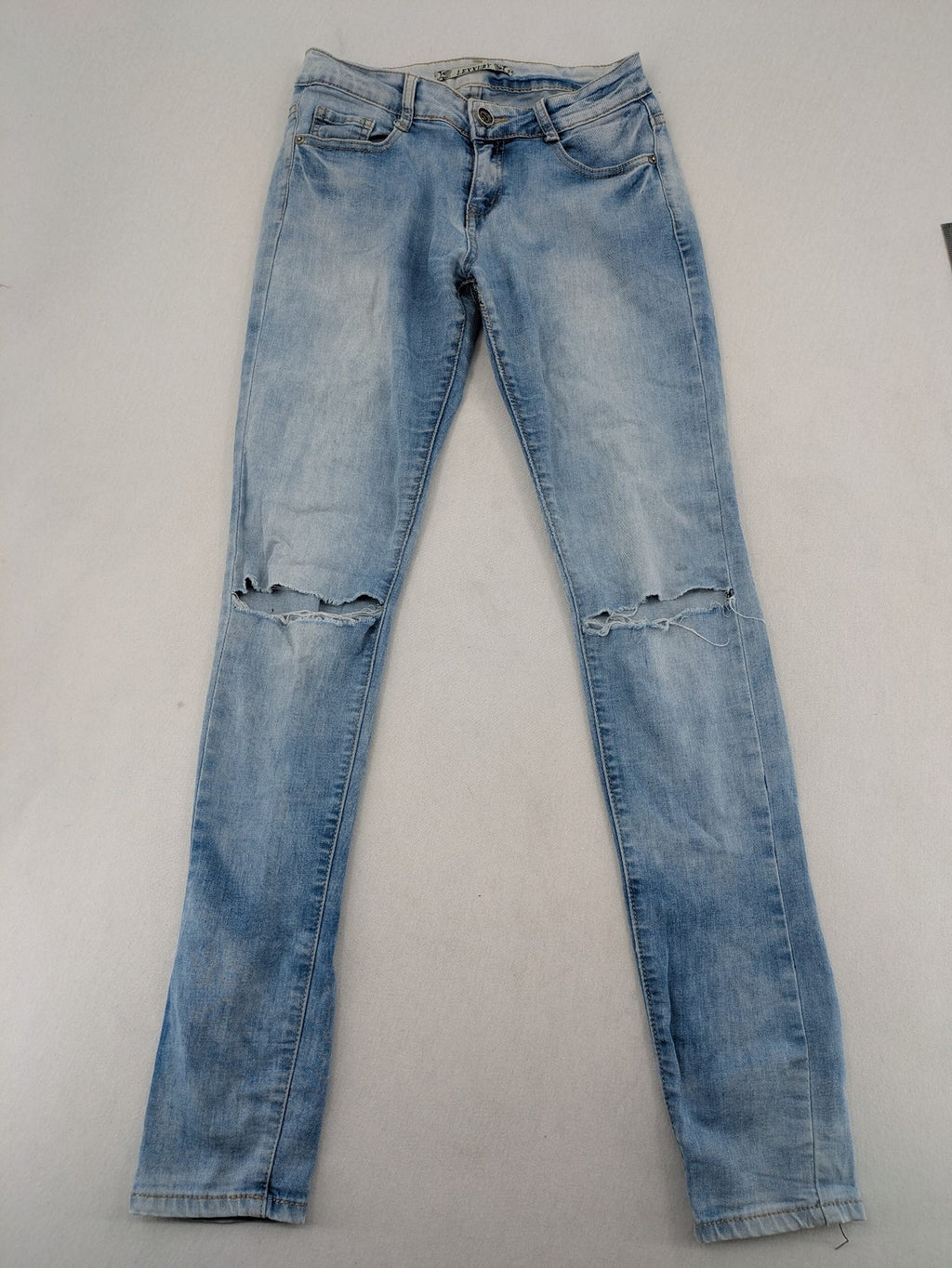 Lexxury blue skinny jeans distressed with knee rips and light wash finish.