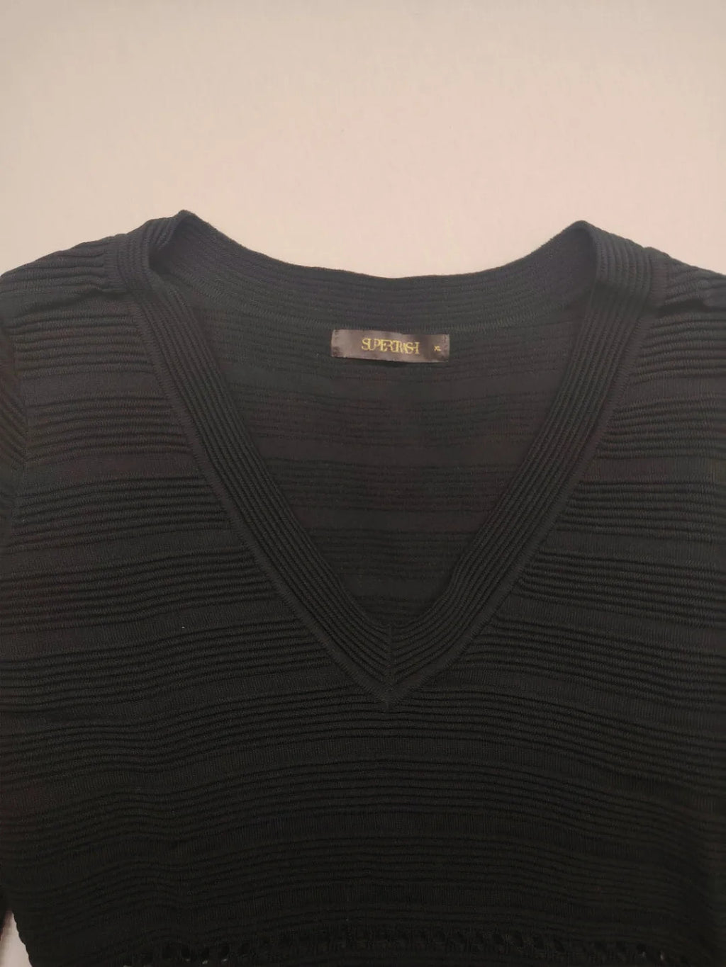 Supertuga black ribbed dress with V-neck, long sleeves, and pointelle detail at waist.