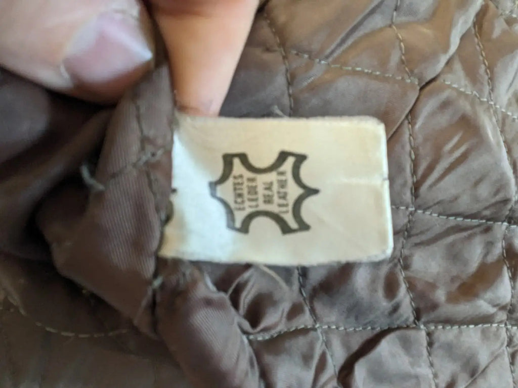 Vintage brown leather jacket with graphic lining, zip closure, and button placket.