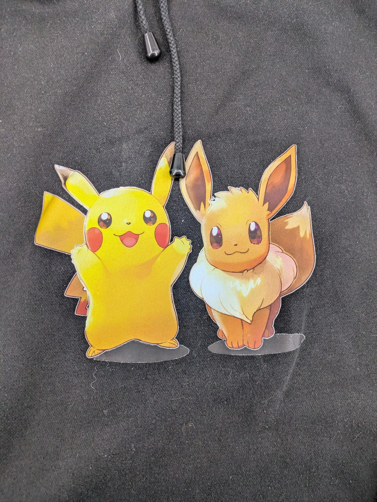 Pokémon black hoodie featuring colorful Pikachu and Evoli graphic, classic pullover style.