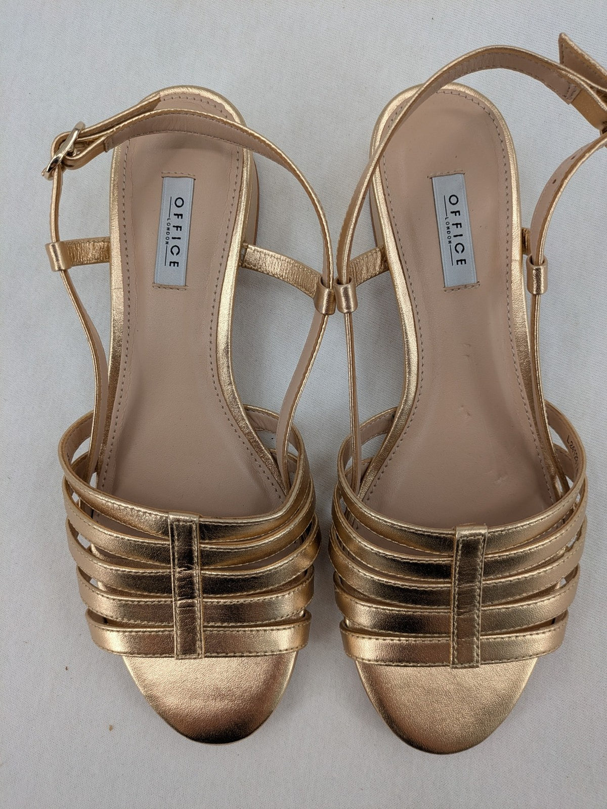 Office London gold metallic sandals with adjustable ankle strap and block heel design.