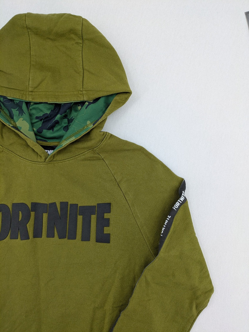 Fortnite green camo hoodie with black logo, contrasting hood, and logo taping on sleeves.