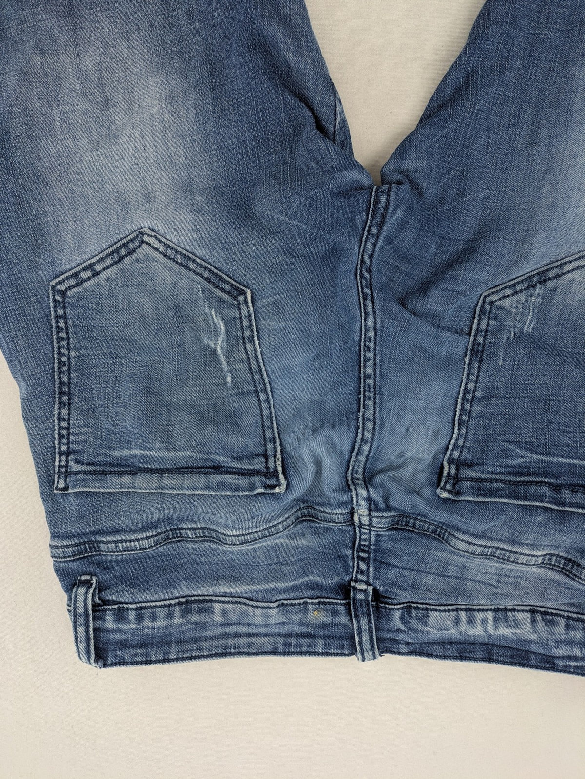 FN.G blue straight jeans with AC/DC patch, smiley face, and elastic jogger cuffs.