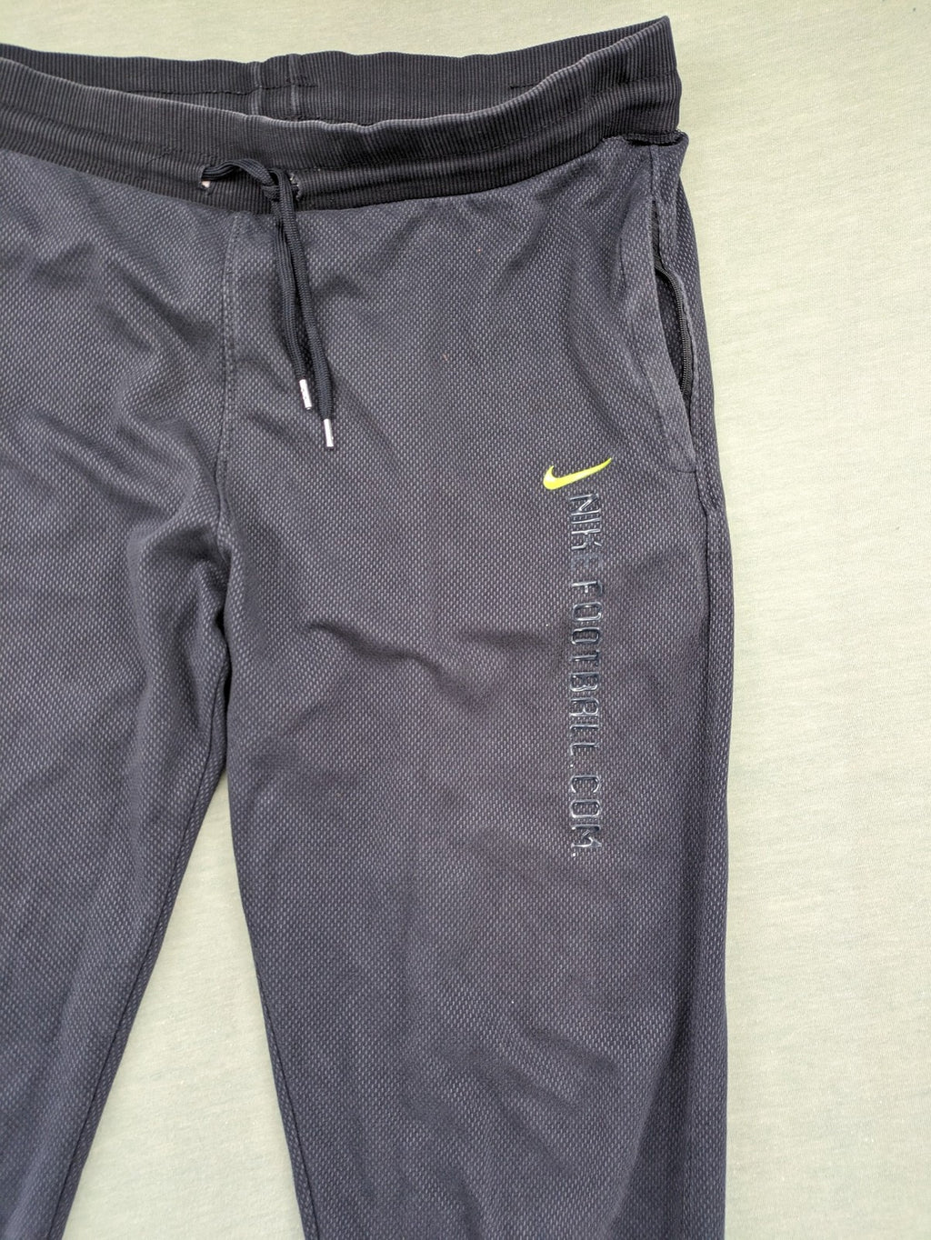 Nike F.C. grey jogger pants with elastic waistband, side pockets, and embroidered Swoosh logo.