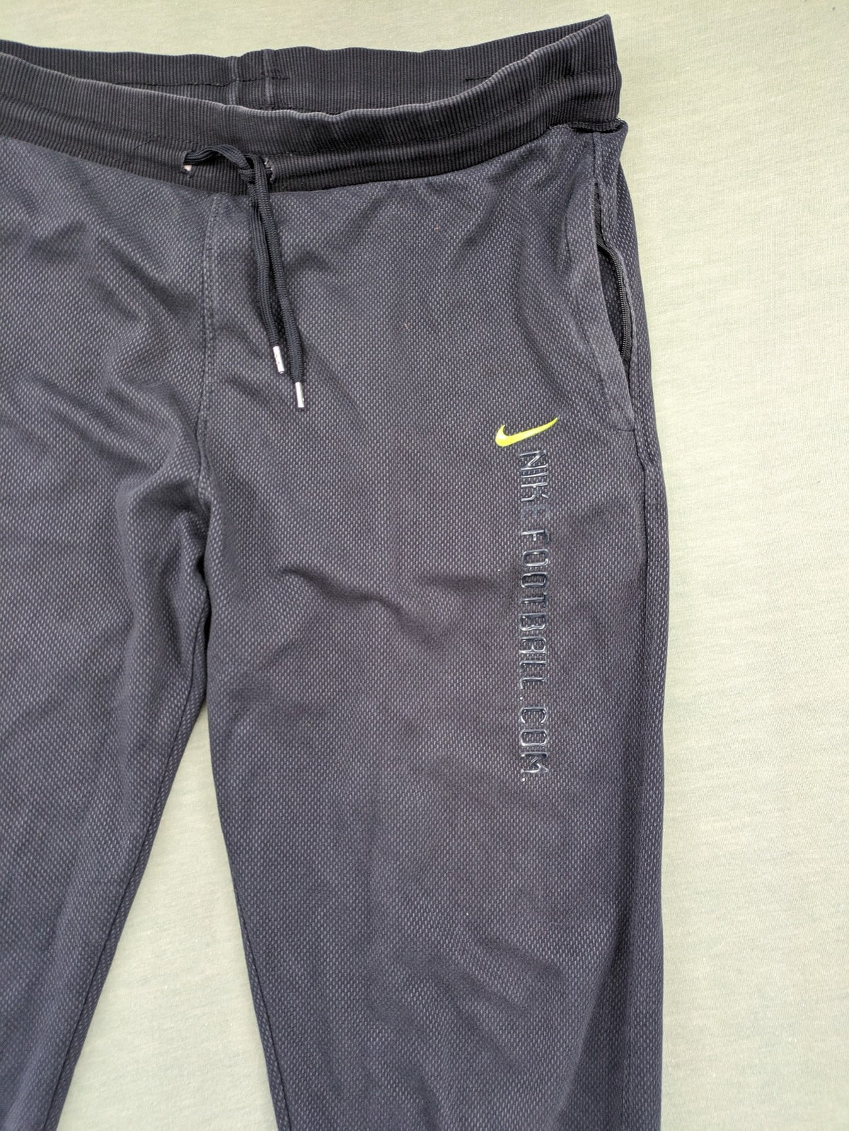 Nike F.C. grey jogger pants with elastic waistband, side pockets, and embroidered Swoosh logo.