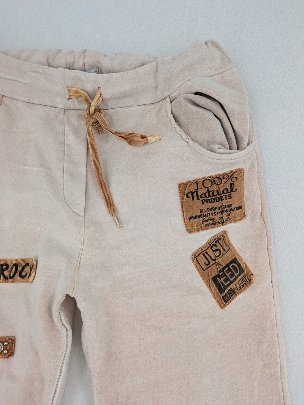 Made In Italy beige pants with crinkle texture and rock-style patches, drawstring waist.