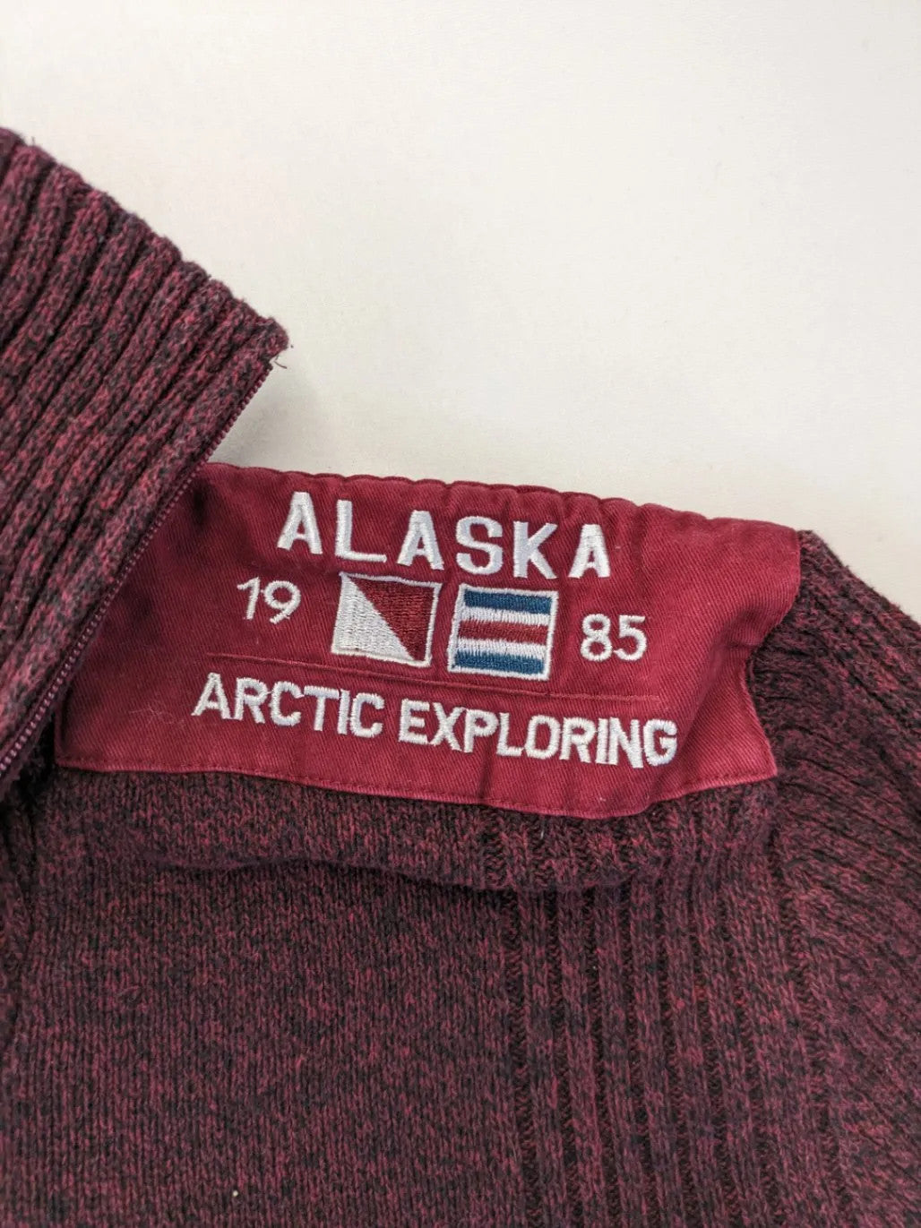 Infinity burgundy turtle neck jumper with quarter-zip and ribbed knit texture.