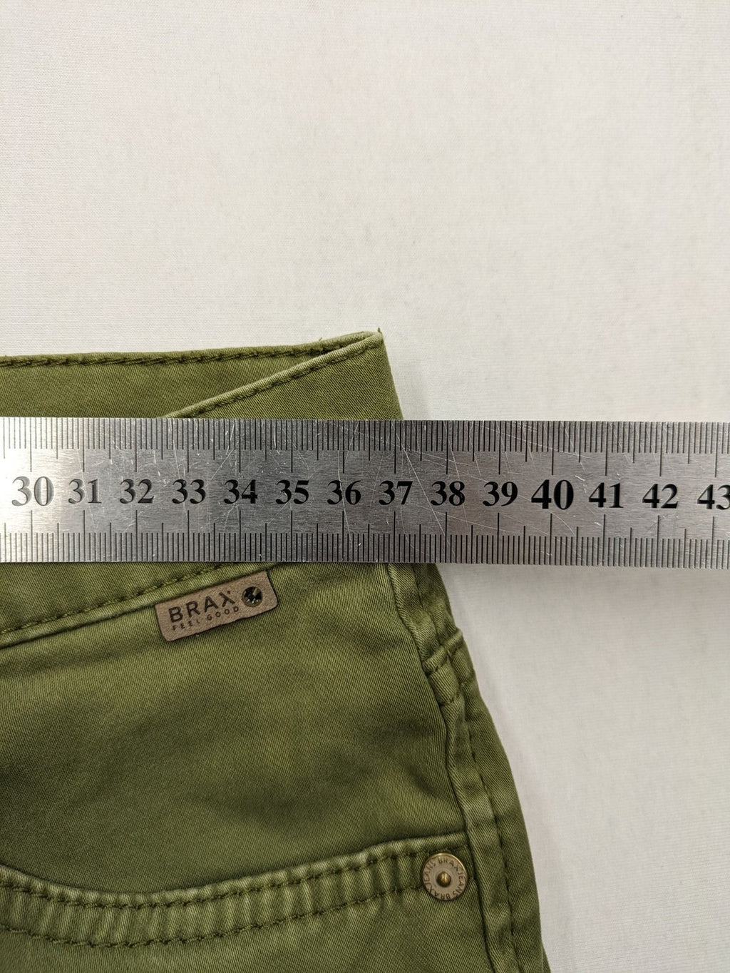 BRAX khaki pants classic five-pocket style with logo patch and zip button closure.