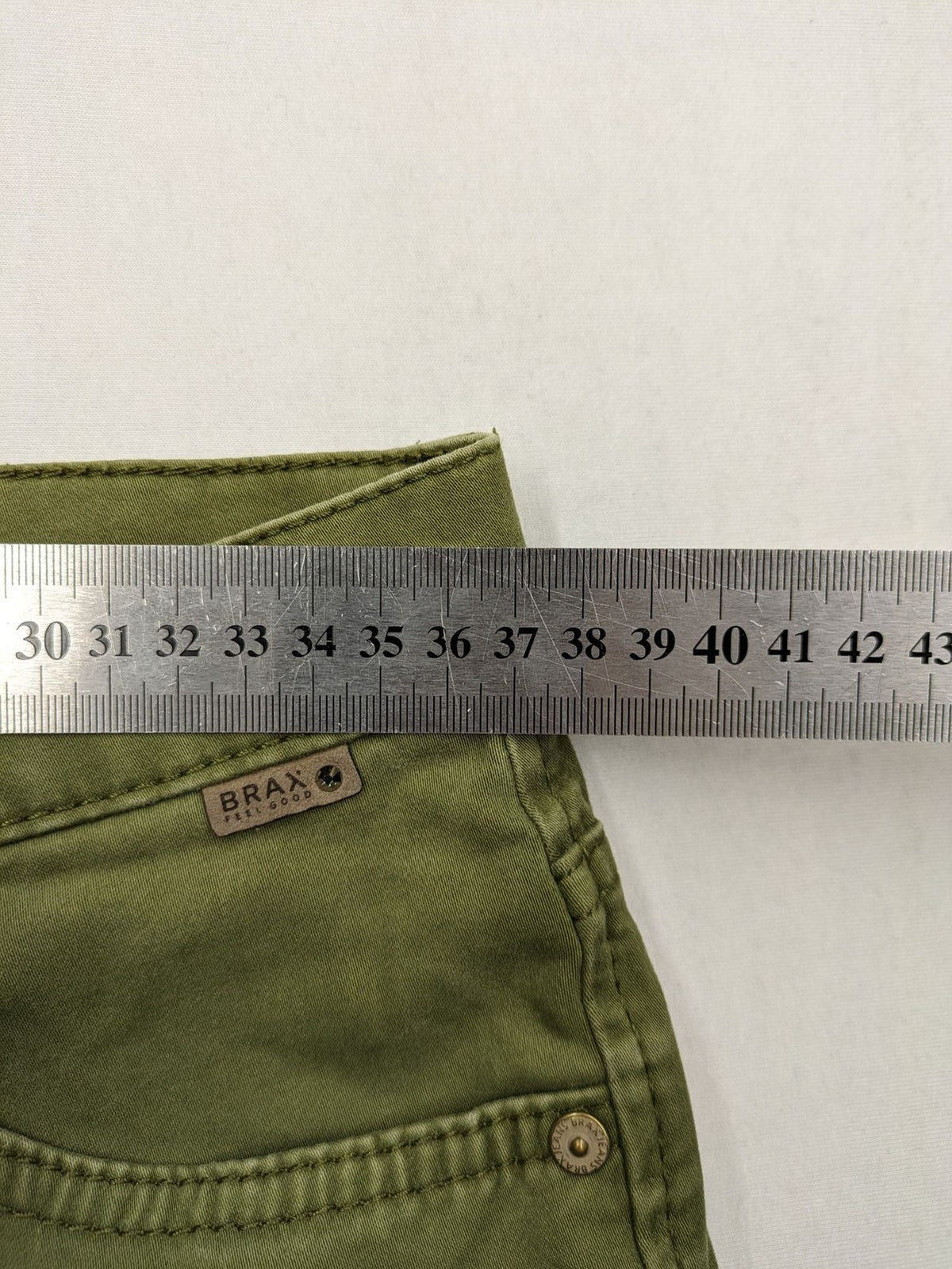 BRAX khaki pants classic five-pocket style with logo patch and zip button closure.