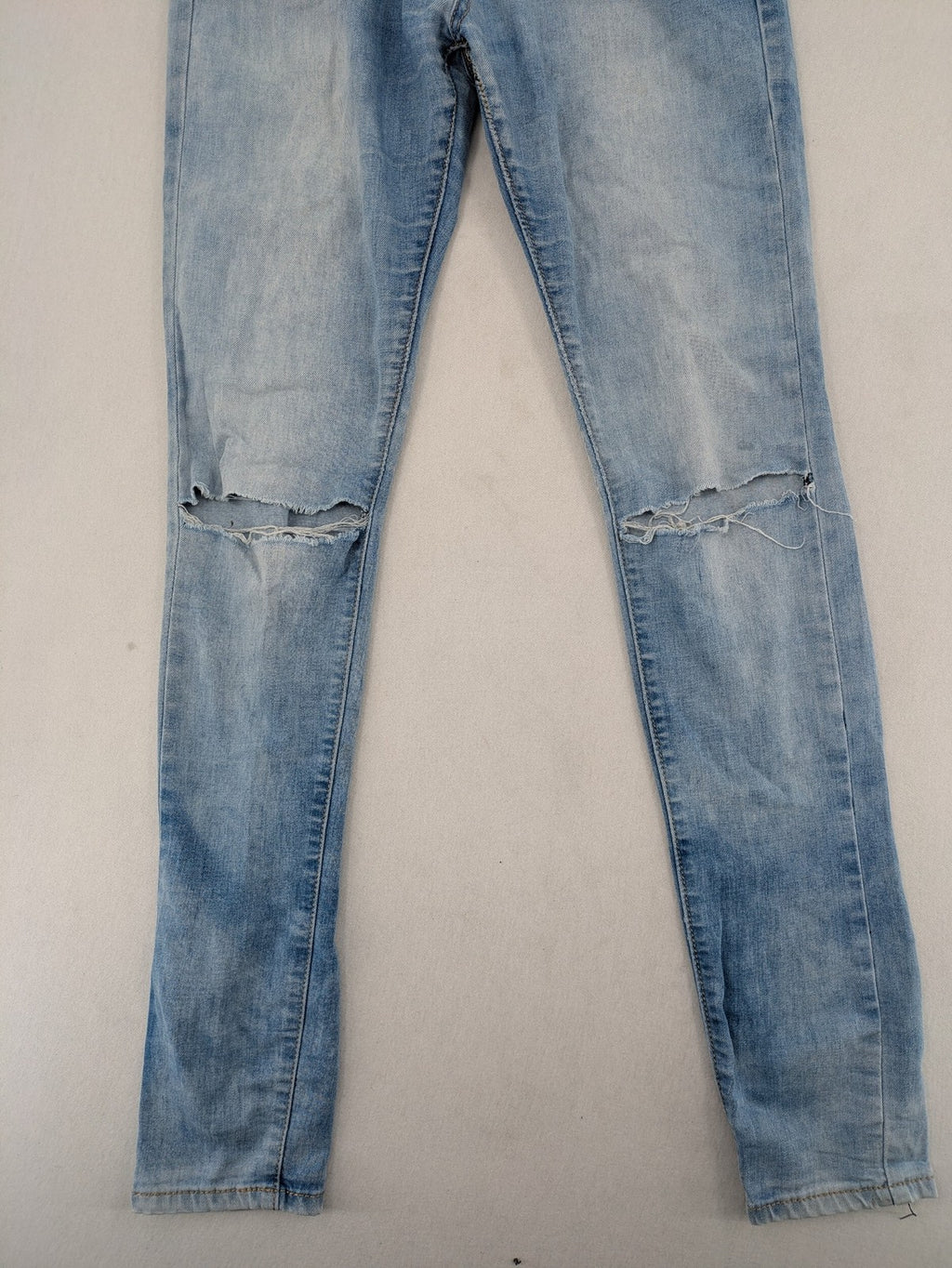 Lexxury blue skinny jeans distressed with knee rips and light wash finish.