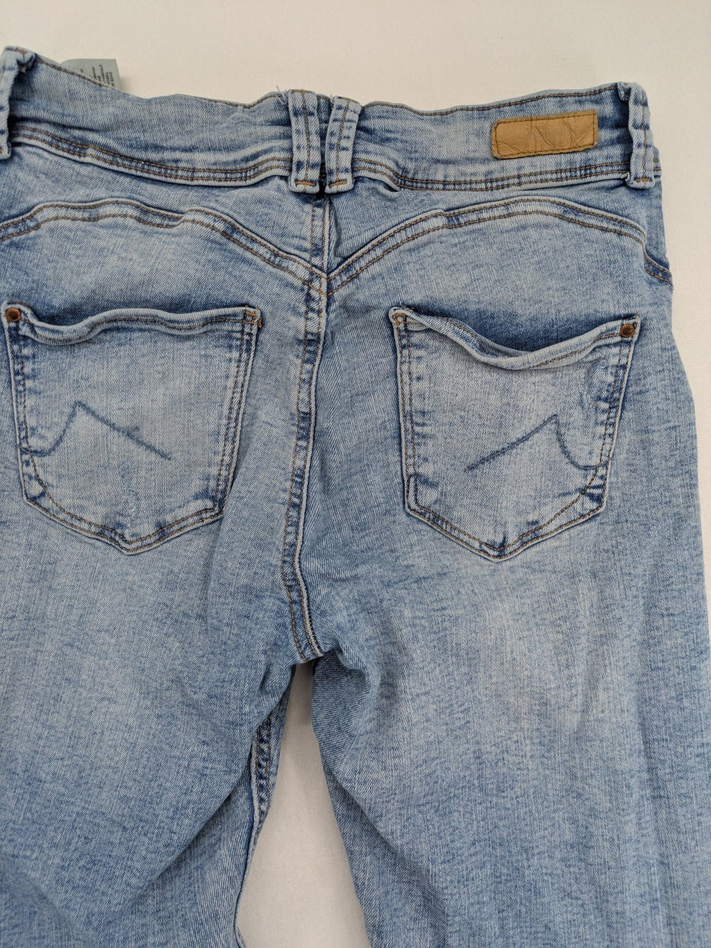 Clockhouse blue skinny jeans with distressed details and frayed hem, mid-rise fit.