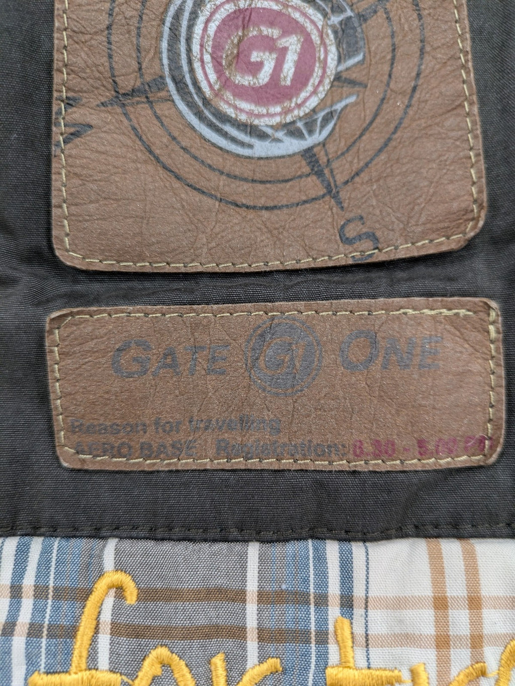 Gate One brown field jacket with plaid lining, multiple pockets, and zip-button closure.
