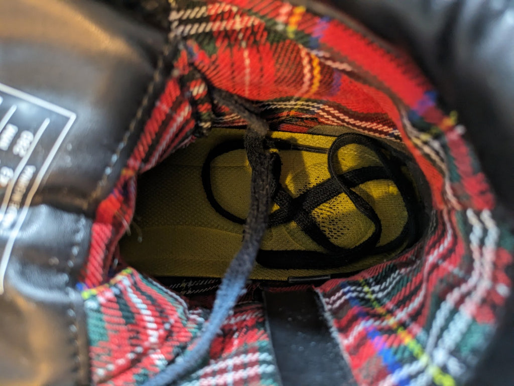 Buffalo black motorcycle boots with chunky sole, adjustable buckle strap, and red plaid lining.