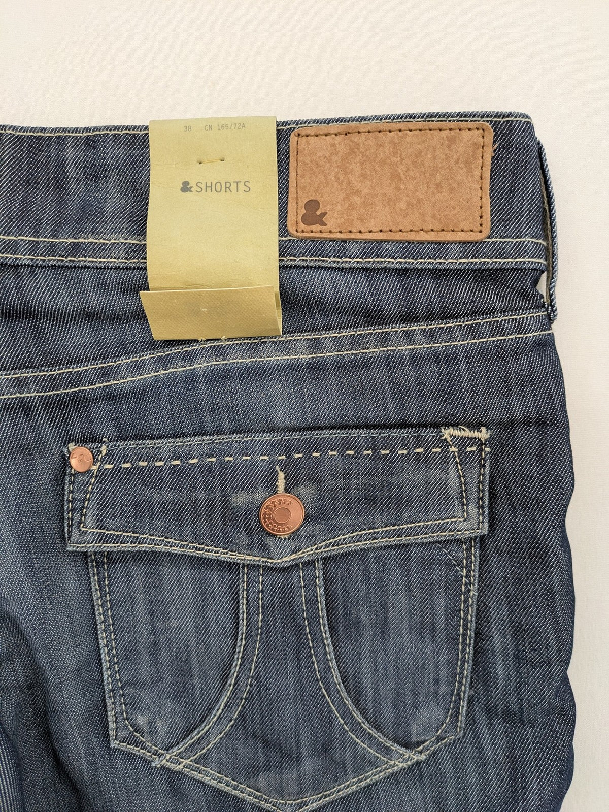 H&M blue denim shorts with rolled cuffs and back patch pockets, mid-rise fit.