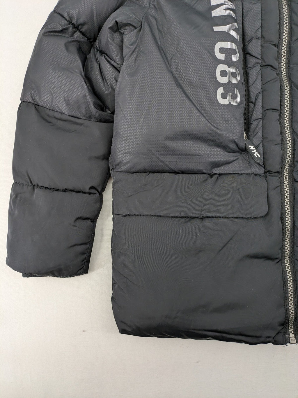 C&A black puffer jacket with NYC83 graphic, hood, and multiple pockets.