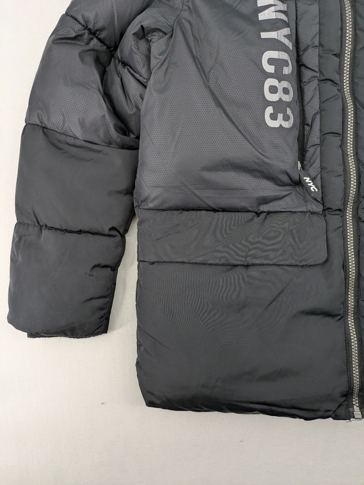 C&A black puffer jacket with NYC83 graphic, hood, and multiple pockets.