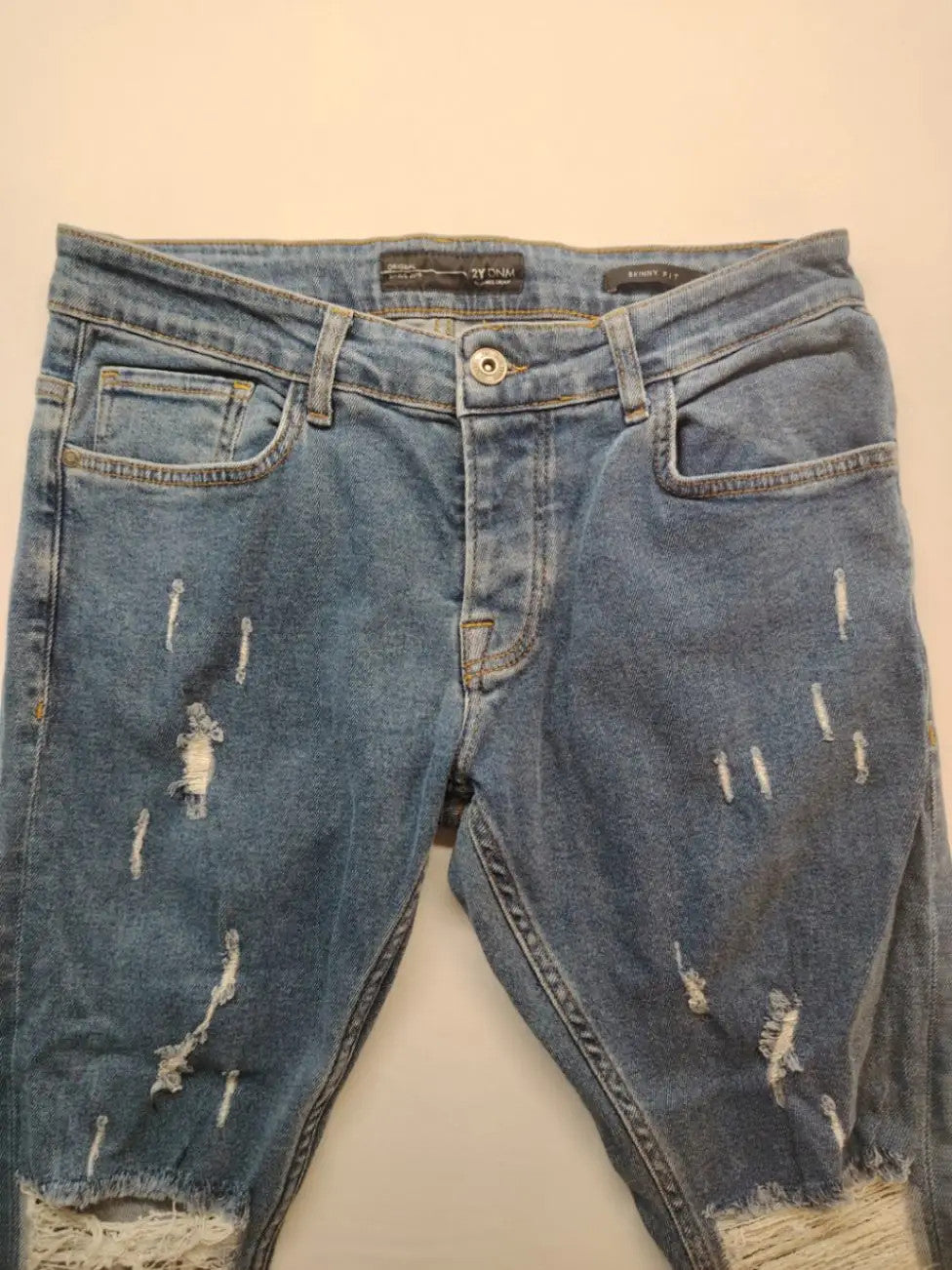 Damen blue skinny jeans with ripped details, five-pocket style, and classic button closure.
