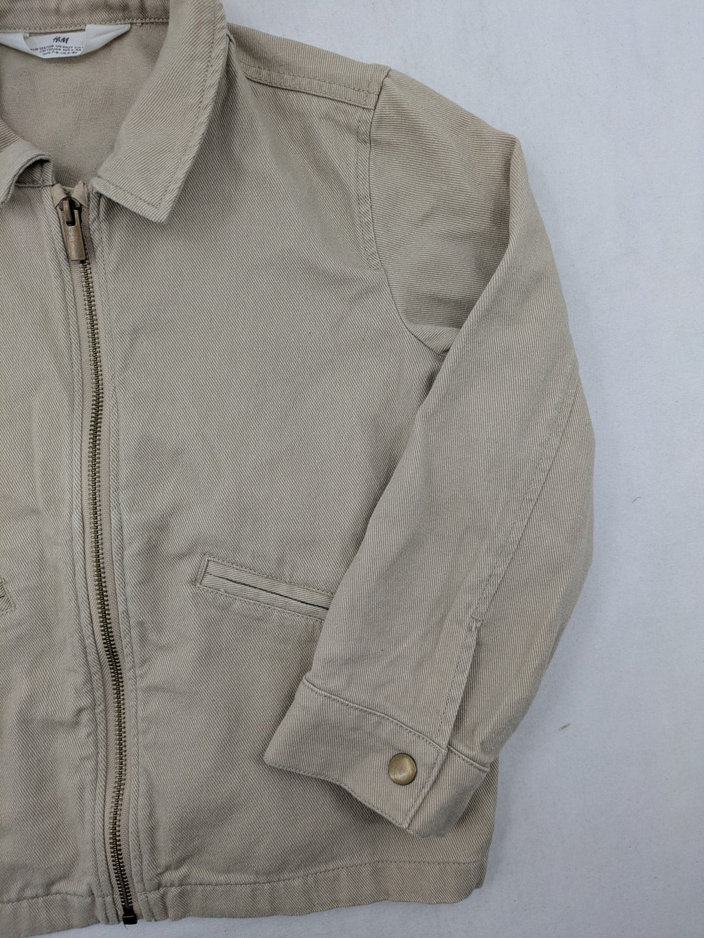 H&M beige twill coat with full zip, classic collar, and practical pockets.