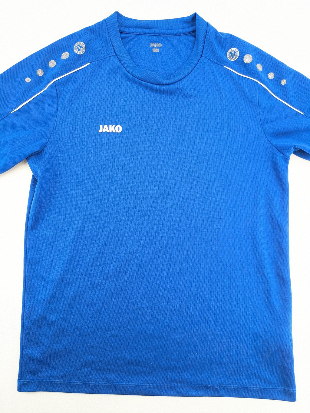 Jako blue short-sleeve training shirt with logo details and breathable polyester material.