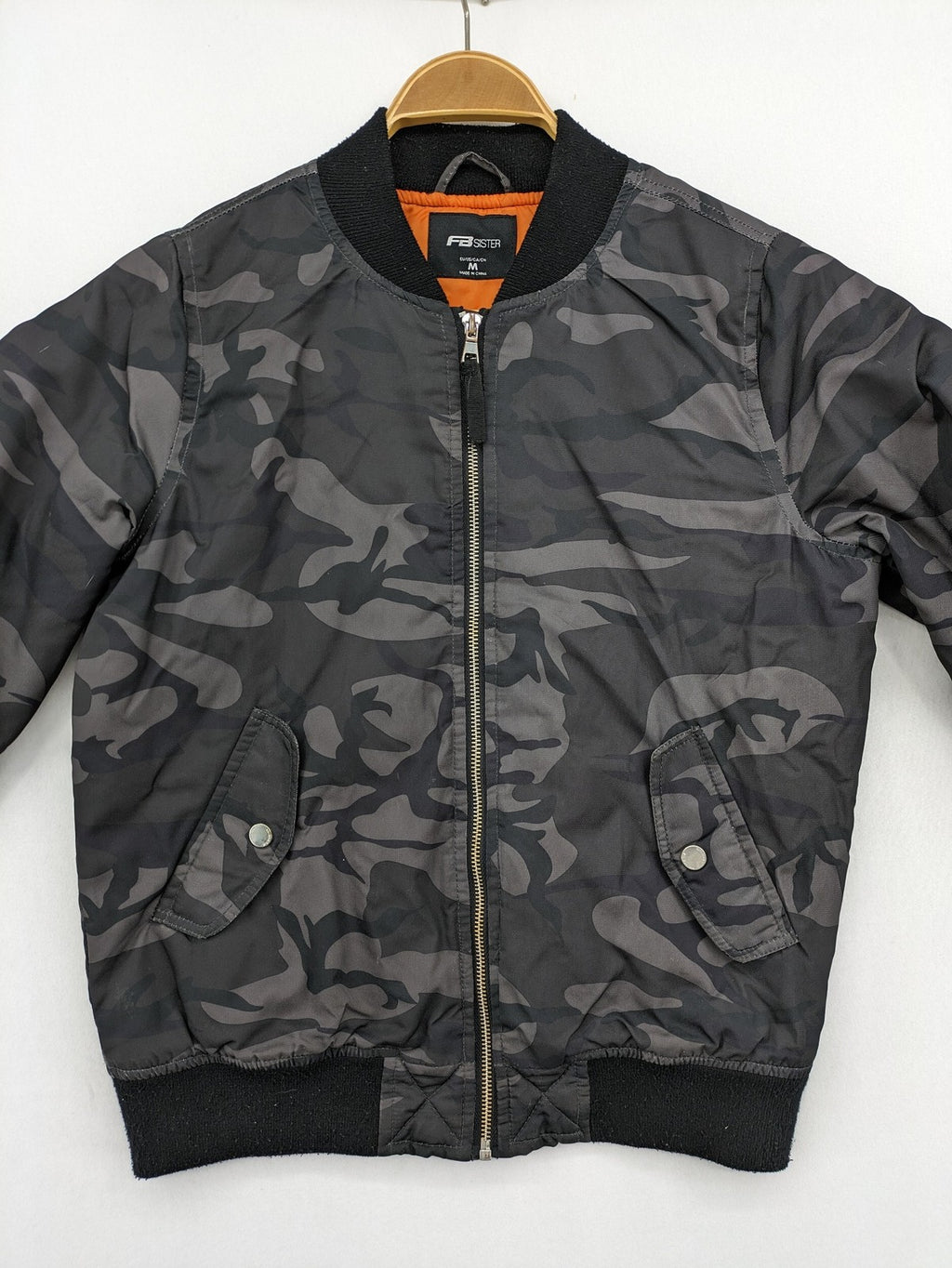 FB Sister orange bomber jacket with gray camouflage pattern and quilted lining.