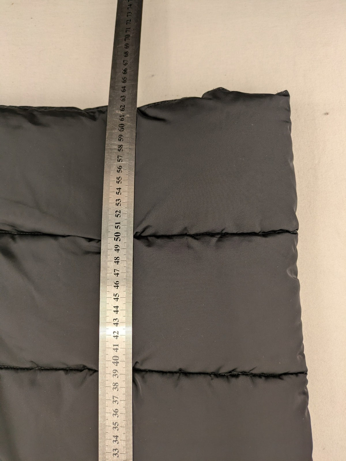C&A black puffer jacket with NYC83 graphic, hood, and multiple pockets.