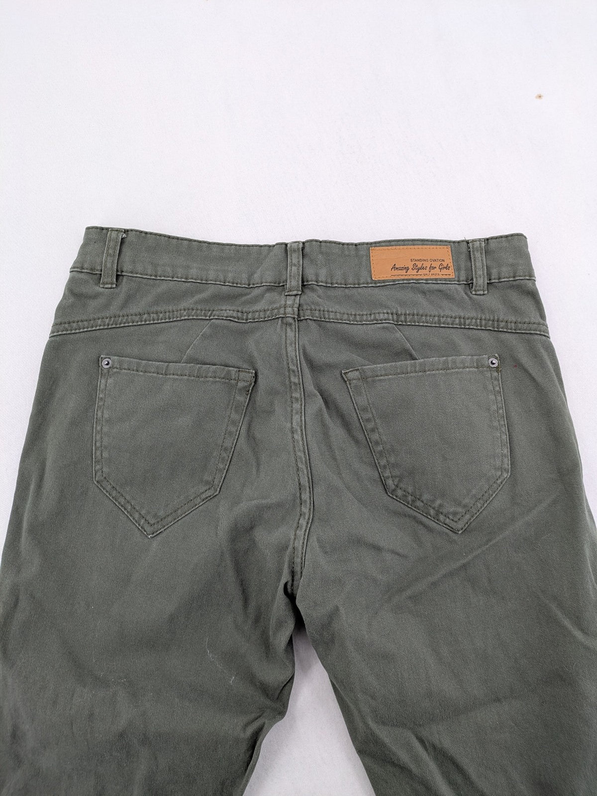 Page One Young khaki motorcycle pants with stitched panels and decorative zipper details.