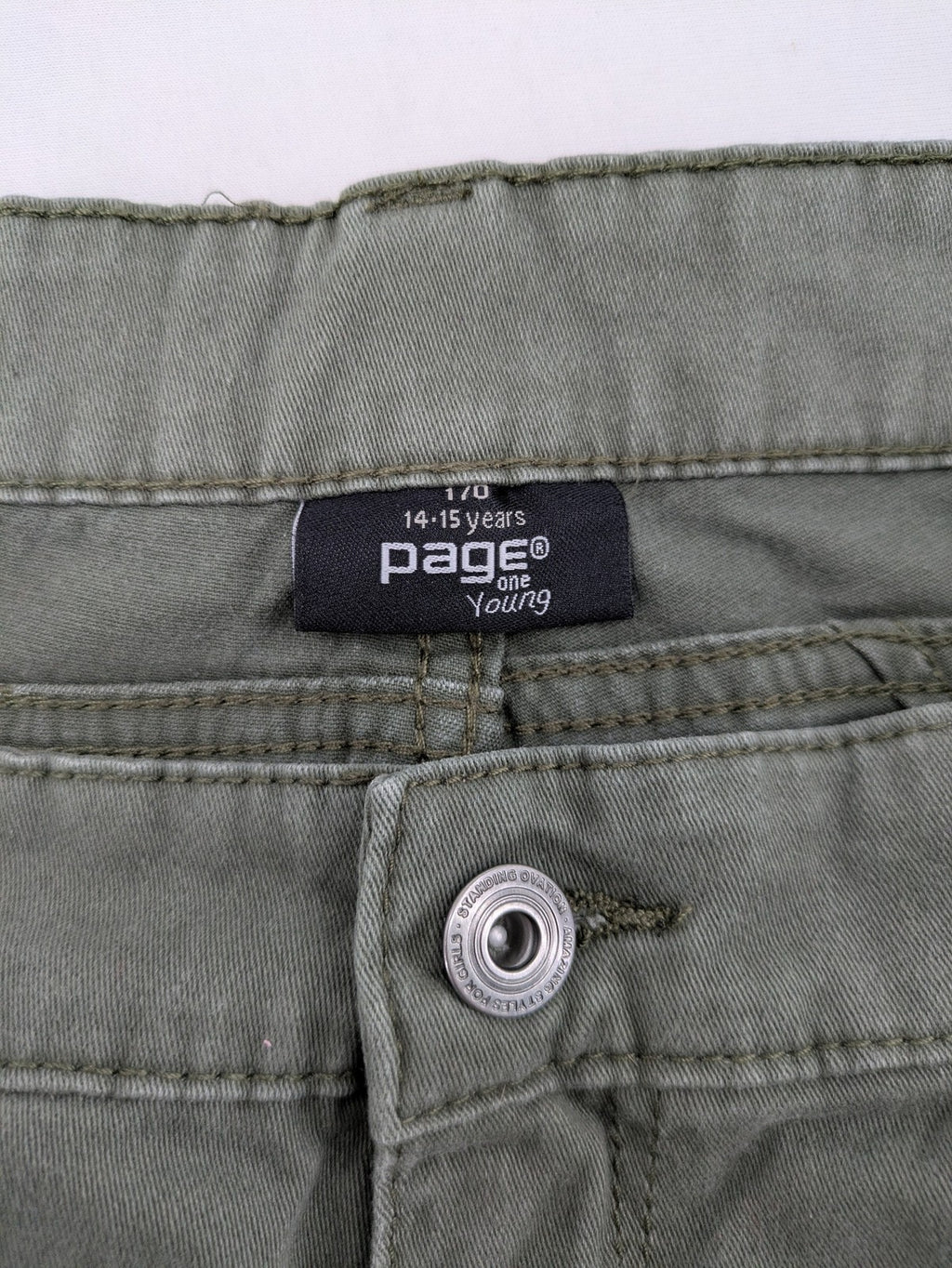 Page One Young khaki motorcycle pants with stitched panels and decorative zipper details.