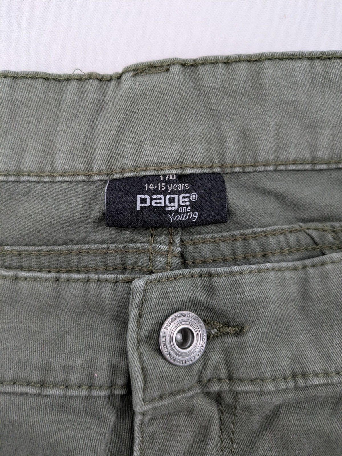 Page One Young khaki motorcycle pants with stitched panels and decorative zipper details.