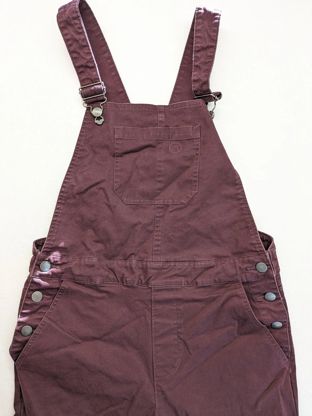 Kazane burgundy overalls with adjustable straps, side button placket, and chest pocket.