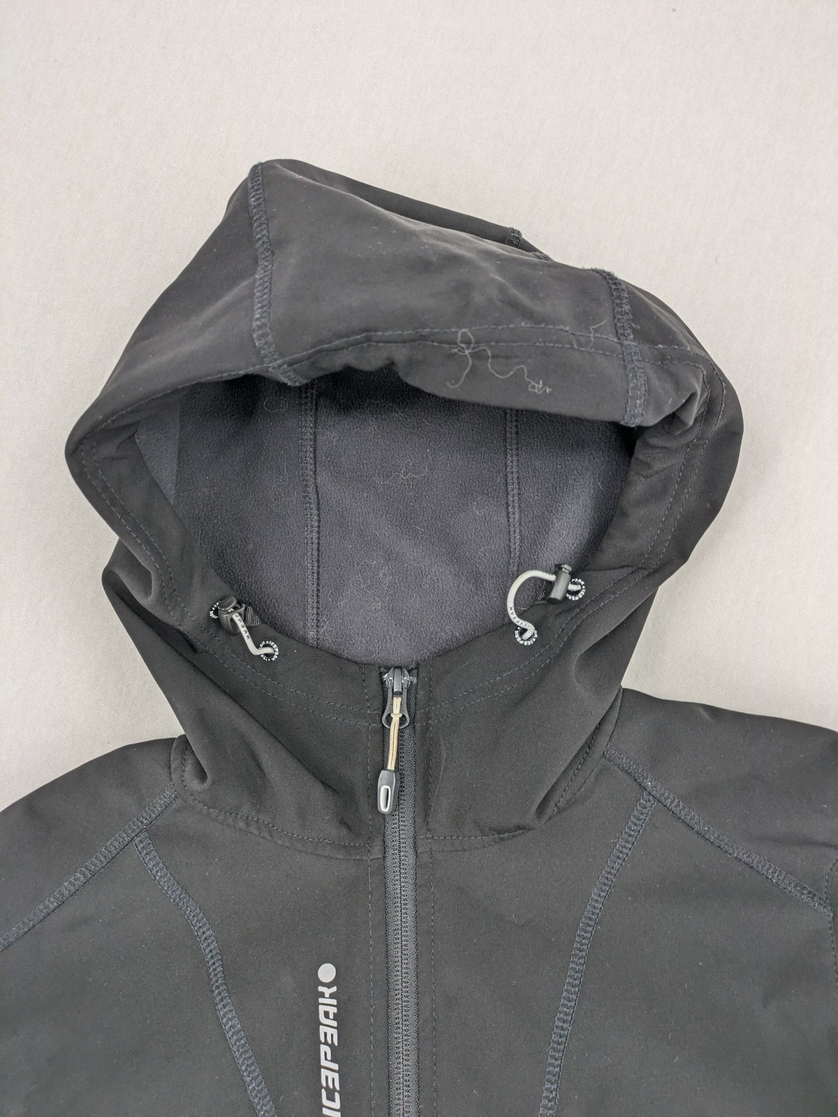 Icepeak black softshell jacket with fleece lining, adjustable hood, and zippered pockets.