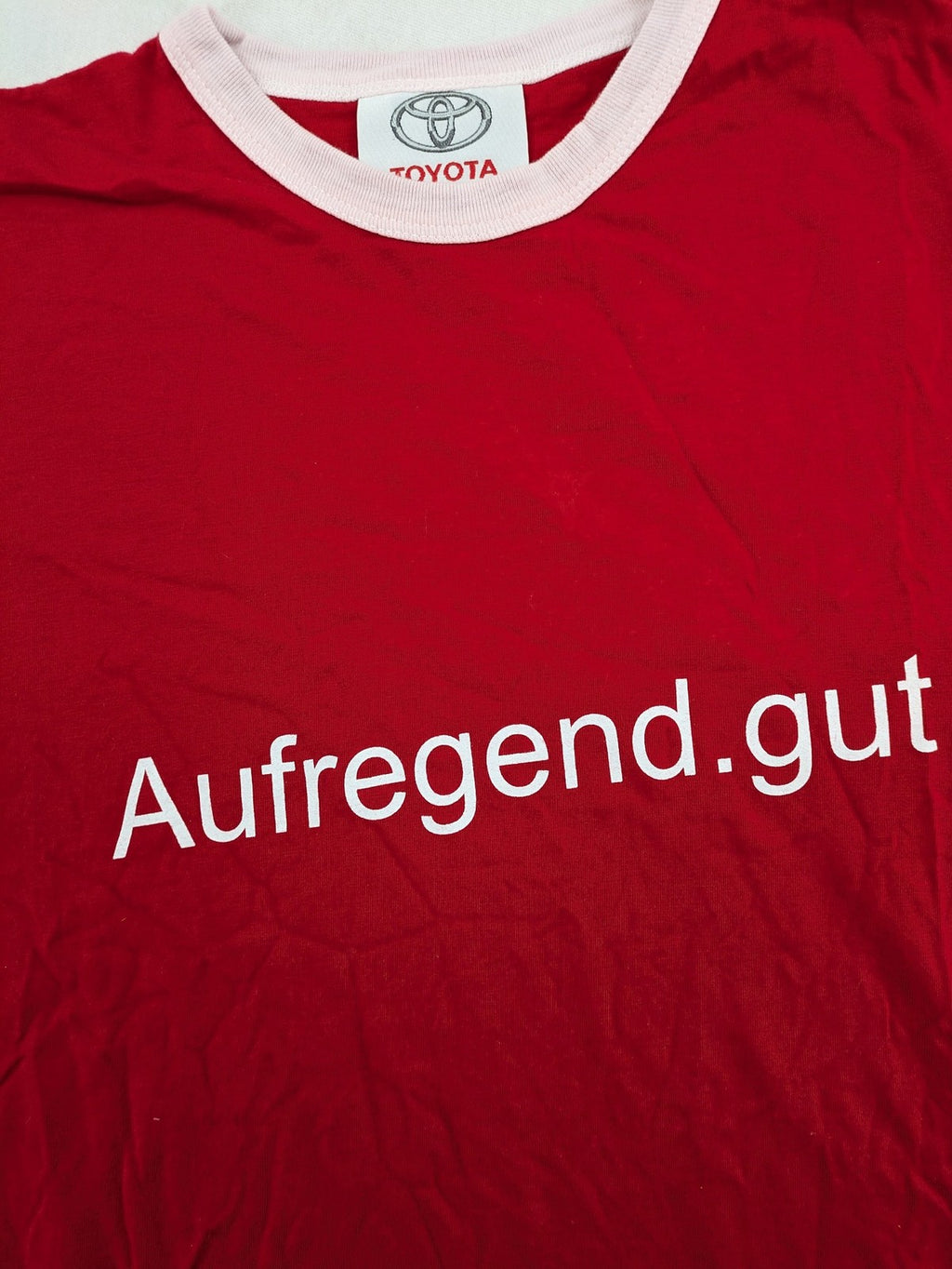 ck red Ringer T-shirt with white collar, "Aufregend.gut" slogan, 100% cotton.