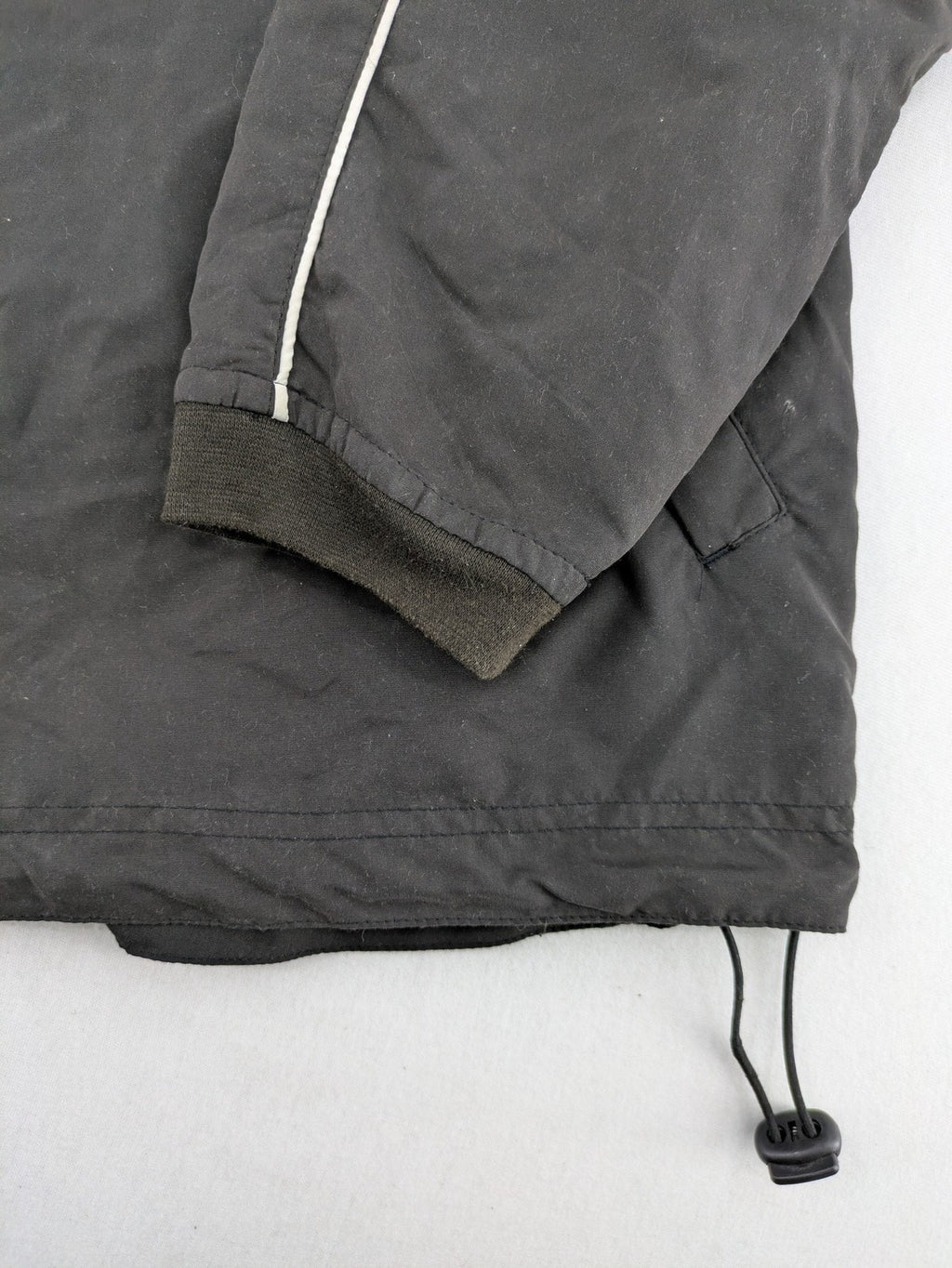Tombo green windbreaker jacket with white piping, V-neck, and zippered pockets.